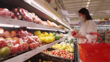 Yeni normal sosyal mesafeli konsept Asyalı kadın koruyucu yüz maskesi takıyor ve marketten meyve seçiyor. Coronavirüs sonrası markette meyve satan kadınlar, covid-19 salgını