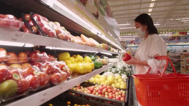 新しい通常の社会的距離概念スーパーマーケットでいくつかの果物を選択保護顔マスクを身に着けてアジアの女性 女性はコロナウイルスの後の間にスーパーマーケットで果物を買い物 Covid 19流行 — ストック動画