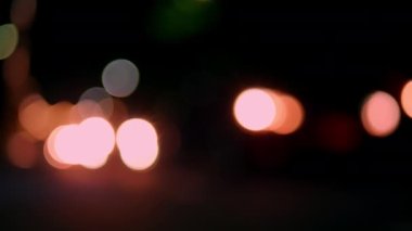 Gece vakti farlı arabanın Bokeh ışığı. Bokeh ışıkları şehrin arka planında. Gece yol ışıkları, gece yoldaki trafikte arabaları bulanıklaştırdı..