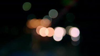 Gece vakti farlı arabanın Bokeh ışığı. Bokeh ışıkları şehrin arka planında. Gece yol ışıkları, gece yoldaki trafikte arabaları bulanıklaştırdı..