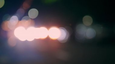 Gece vakti farlı arabanın Bokeh ışığı. Bokeh ışıkları şehrin arka planında. Gece yol ışıkları, gece yoldaki trafikte arabaları bulanıklaştırdı..