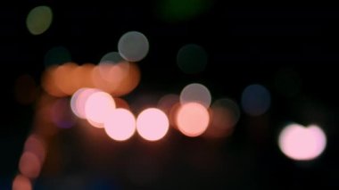 Gece vakti farlı arabanın Bokeh ışığı. Bokeh ışıkları şehrin arka planında. Gece yol ışıkları, gece yoldaki trafikte arabaları bulanıklaştırdı..