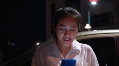 Gece vakti akıllı telefon kullanan Asyalı gülümseyen kadın. Kadınlar şehirde yürürken telefonda sohbet ediyorlar. Sokakta tek başına dolaşan bir kadın, gece yolundaki arkadaşıyla akıllı telefon iletişimi kuruyor. Yaşam tarzı kavramı