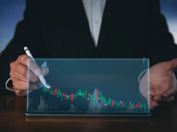 Businessman writing analyze graph for trade stock market on tablet screen. Businessman hand drawing chart graph stock of growth. Hand man uses pen to draw stock graph chart point of target success.