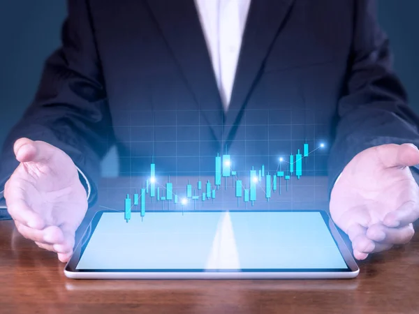 Hand of businessman present tablet analysis stock market graph growth and increase of chart positive indicators. Hand holding tablet show stock chart on blue background.