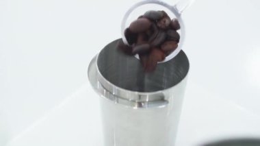 Close up the Barista's hand is scooping coffee beans and pouring them into a measuring cup. Coffee shop balista make coffee with digital scales