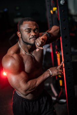 Spor salonunda çıplak gövdesi olan güçlü bir sporcu. Kameraya poz veren kaslı üstsüz vücut geliştirici..