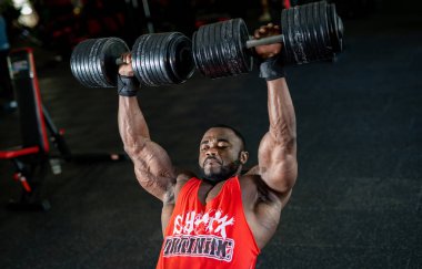 Ağır kilolu kaslı adam eğitimi. Atletik sporcu vücut geliştirici büyük ağırlıklarla egzersiz yapıyor..