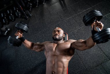 Sporcu adam elleri ve sırtı için egzersiz yapıyor. Spor salonundaki Afrikalı sporcu. Düşük açı. Spor konsepti