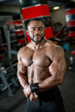 Vücut geliştirici poz veriyor. Güzel sporcu erkek gücü. Spor salonu geçmişi olan, gömleksiz kaslı bir adam.