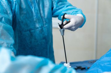 Operasyonda, elinde bazı aletler bulunan ve operasyona hazırlanan, konsantre ve nitelikli bir doktor. Kırpılmış görünüm