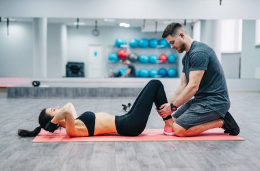 Kadının karın egzersizi basın egzersiz onu spor erkek antrenman ör içinde jimnastik salonu ile mindere yapması. Çift egzersizleri üzerinde arka plan bulanık spor salonu