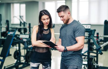 Antrenör ve müvekkil spor salonunda onun gelişimini tartışıyor. Panoya yazı yazan beden eğitimi hocası. Stok fotoğrafı