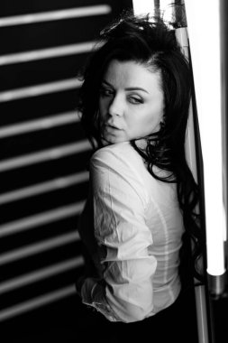 Disko ışıkları odada. Beyaz gömlekli kız kameraya poz veriyor. Fütüristik iç mekanda esmer. Siyah beyaz portre