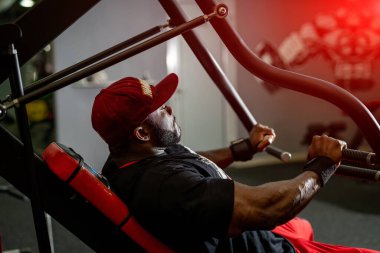 Spor kıyafetlerindeki kaslı adam sıkı çalışıyor. Spor salonunda çalışan yakışıklı bir vücut geliştirici..