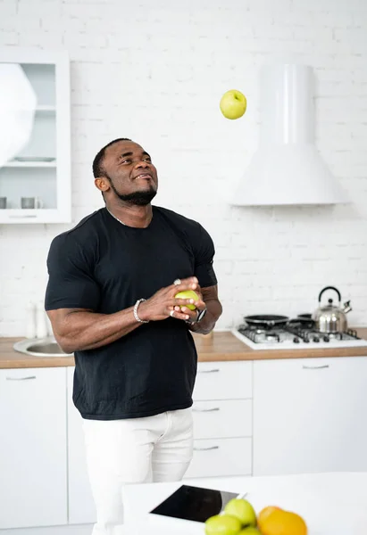 快乐的年轻的多种族男子在厨房背景下慢跑苹果 有选择的焦点 节食的概念 — 图库照片