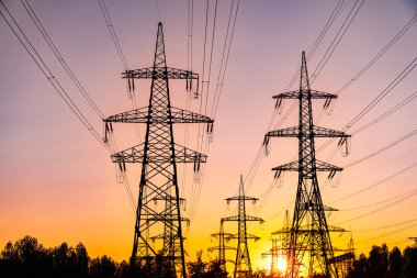 Gün batımında yüksek voltaj kulelerinin gölgeleri. Koyu elektrik güç siluetleri.