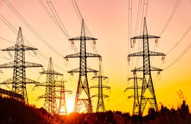 Koyu elektrik güç siluetleri. Gün batımında yüksek voltaj kulelerinin gölgeleri.