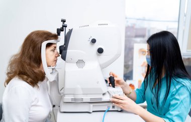 Görüşü test ederken refraktometre kullanan kadın optometristin portresini kapat. Klinikteki kadın hasta. Belini kaldır.