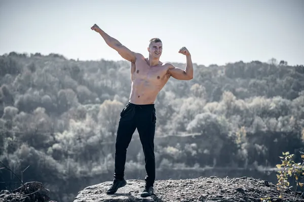 強い筋肉の男の風景の上に屋外に立っている 屋外をポーズスポーツボディビルダー — ストック写真