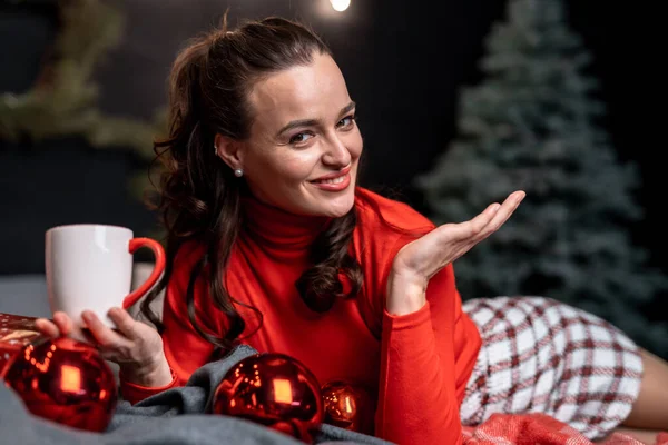 크리스마스 장식으로 둘러싸인 빛나는 스웨터입은 여자와 스커트 어두운 배경에 크리스마스 — 스톡 사진