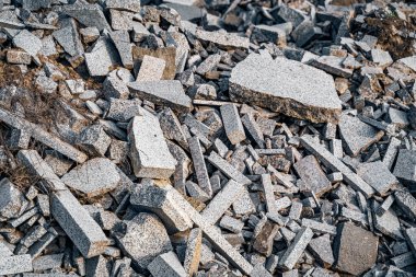 Kırık granit parçaları. Düz kenarlı taş artıkları dışarıda bir yerde bir yığın halinde yatıyor. İnşaat alanında granit artıkları birikmiş..