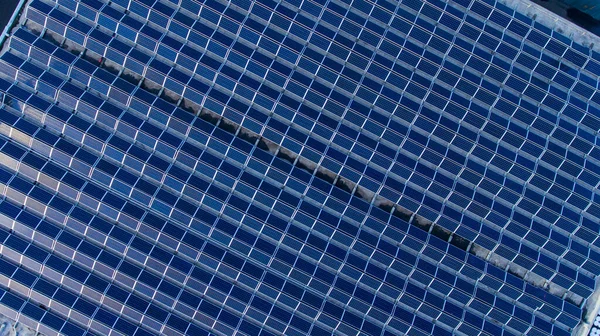 建物の上には青い太陽光発電パネルがたくさんあります 太陽電池で密に覆われた平らな屋根 上からの眺め — ストック写真