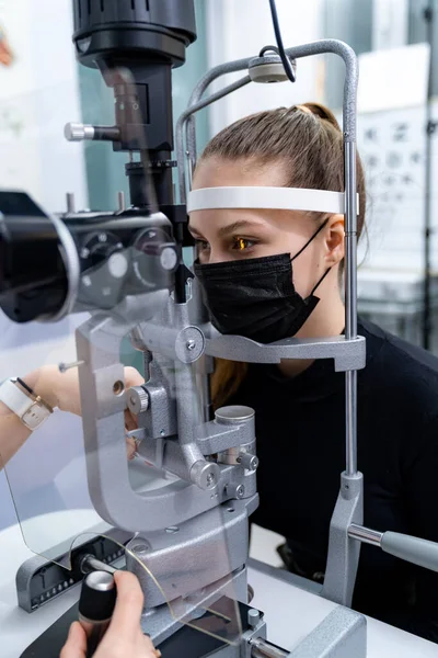 Woman has eyes examined on a slit lamp. Modern equipment for eye sight check up in clinic. Closeup