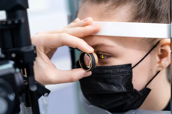 Esmer kadın optometrist, modern ekipmanlarla kadınlara teşhis koyuyor. Sağlıklı gözler için güncel klinik. Yakın çekim.