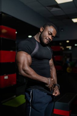 Sportif sporcu, pazılarını spor salonunda çalıştırıyor. Spor salonunda kamera için poz veren genç vücut geliştirici..