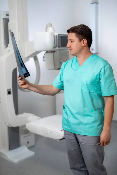 ドキュメントを読みながらカメラにポーズをとった青い服の医者 手術室の近くに立っている医療 垂直表示 — ストック写真