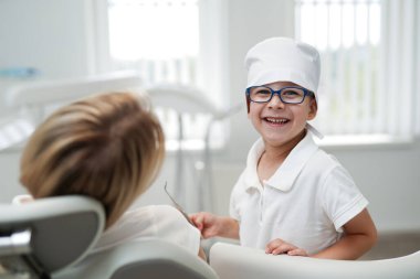 Küçük doktor dişçi çocuk. Gülümseyen çocuk dişçi ekipmanlarıyla oynuyor..