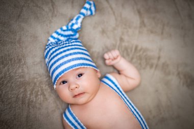 Açık mavi elbiseli yeni doğmuş bebek kameraya bakıyor.