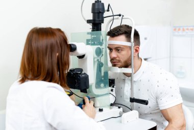Genç bir optometrist hastaların gözlerini muayene ediyor. Optisyen uzman görme testi.