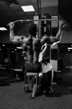 Spor salonunda antrenman yapan güçlü kaslı bir adam. Genç yakışıklı adam ağır yük kaldırıyor..