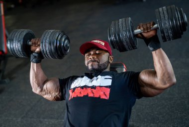 Büyük ağırlıklarla çalışan güçlü ve yakışıklı bir adam. Spor salonundaki kaslı sporcu..