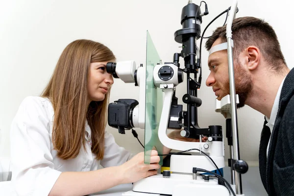 眼科専門医が患者の目を検査します 若い医療専門家による専門的なビジョン診断 — ストック写真
