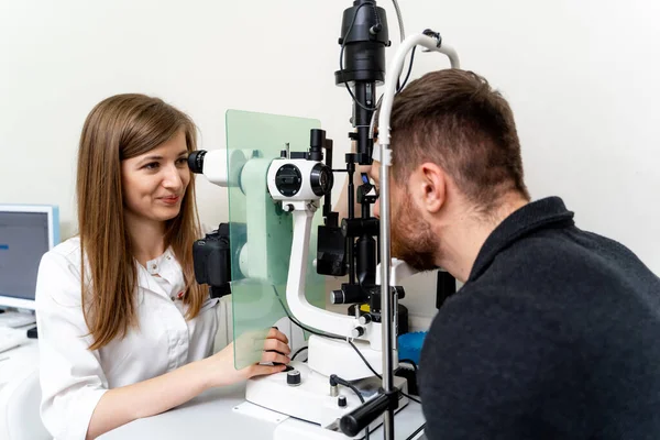 若い医療専門家による専門的なビジョン診断 患者の目を調べる眼科専門医 — ストック写真