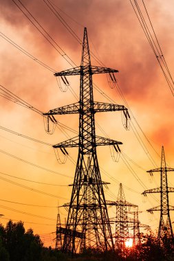 Metal inşaat silueti. Turuncu gün batımında elektrik ikmal kulesi gölgesi.