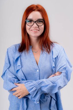 Mavi gömlekli zarif iş kadını stüdyodaki gri arka plandaki kameraya bakıyor. Bir iş kadınının portresi