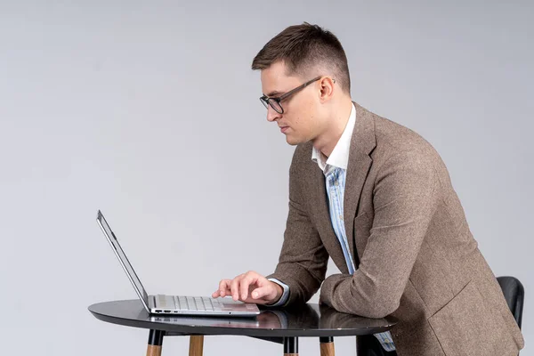 ノートパソコンを机の上に置いたビジネスマン 男でスーツで隔離されたグレーの背景 — ストック写真