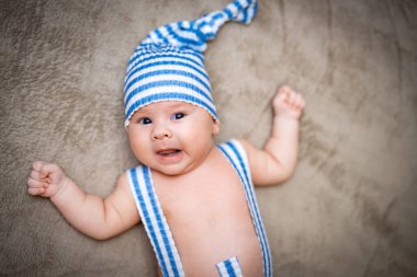 Mavi kostümlü komik bebek. Küçük tatlı çocuk yalan söylüyor.