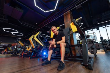 Modern spor salonunda çalışan güçlü bir adam. Genç atletik vücut geliştirici sıkı çalışıyor..