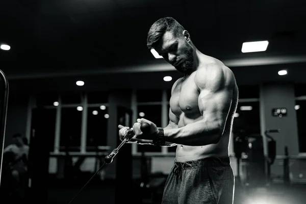 強い筋肉質の男がジムで一生懸命働いている スポーツウェアのスポーツボディビルダー — ストック写真