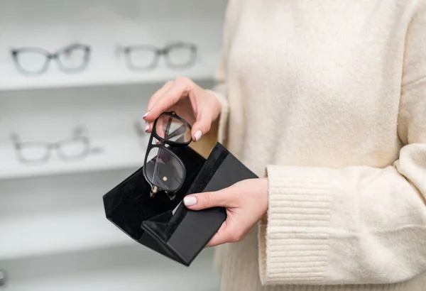 Optical modern frame accessory. Stylish eyewear glasses in woman hands.