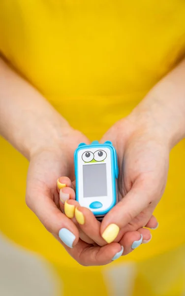 Healthcare monitoring device holding in hands. Woman hands holding a pulse oximetry.