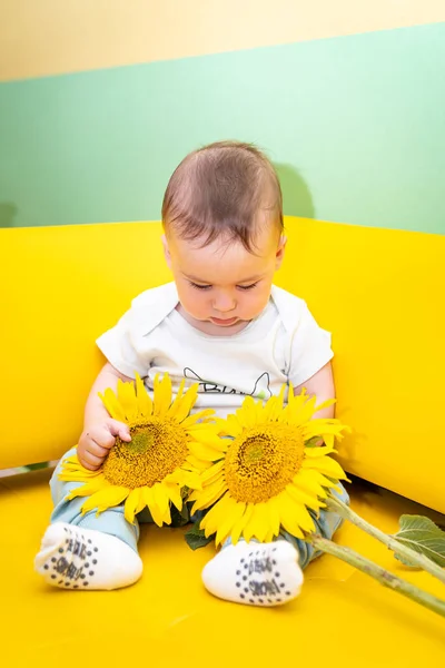 Adorable little kid with flower. Small cute baby sitting with sunflower.