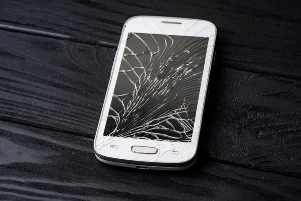 Digital white smartphone with smashed screen. Phone with broken screen.