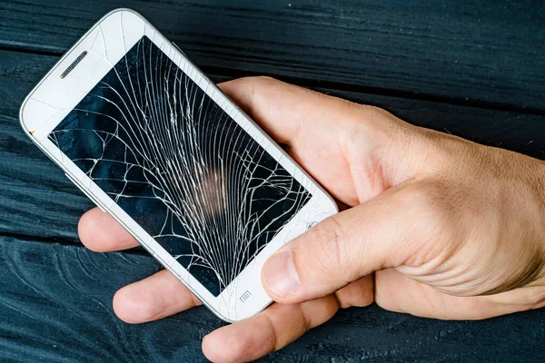 Modern smashed electronic smartphone. Broken cellphone holding in hands.