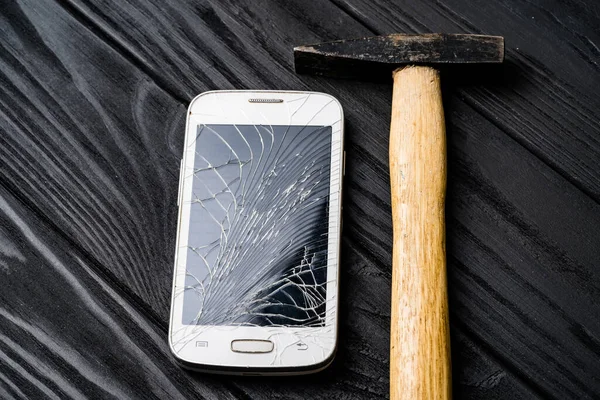 Smashed phone with hammer. Damaged smartphone concept.